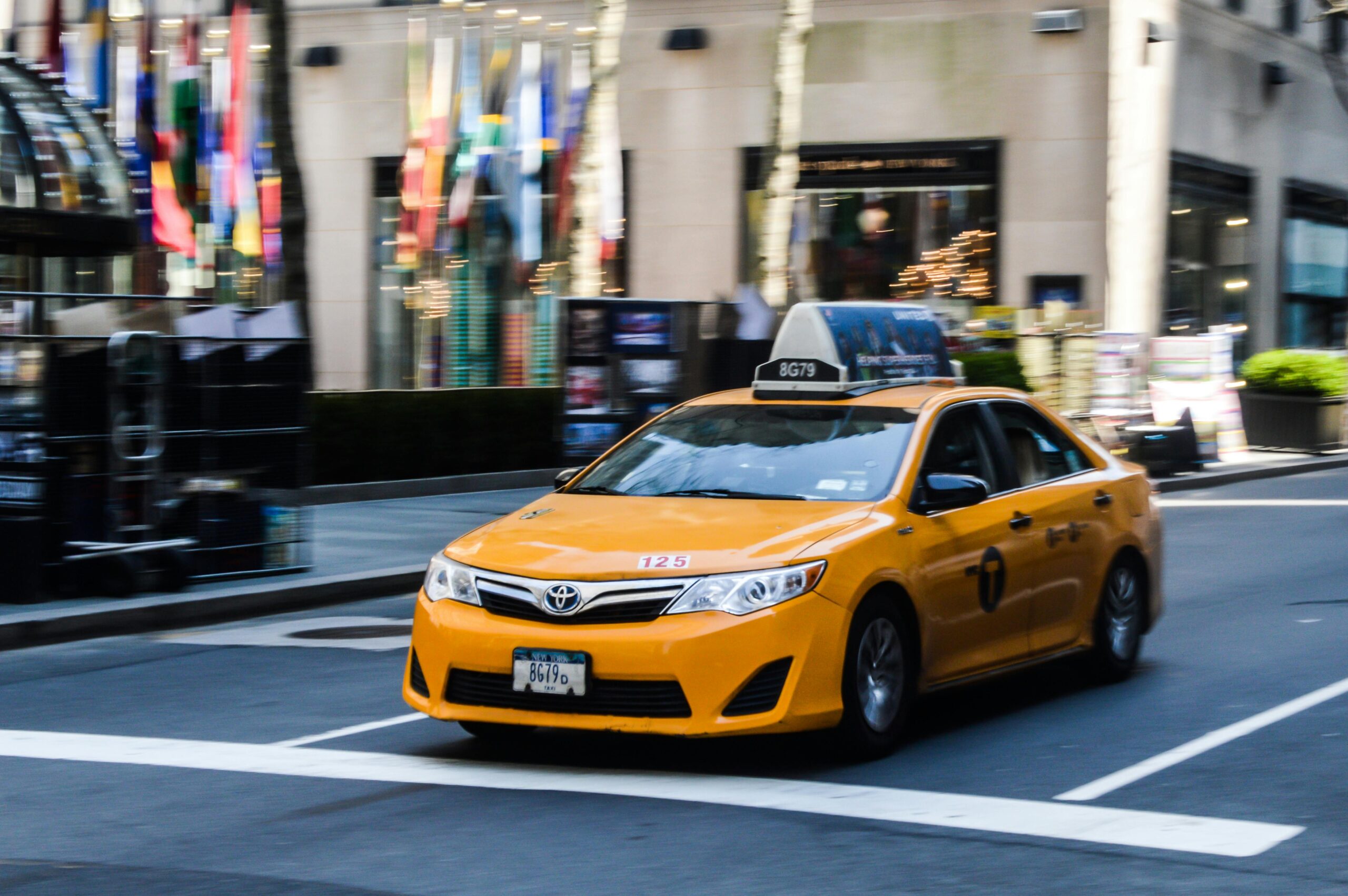 A classic yellow taxi speeds through the streets of New York City, capturing the vibrant urban atmosphere.